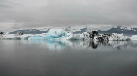 Bright blue peace of ice reflecting in still grey waters of Glacier lagoon Stock Footage 33778475