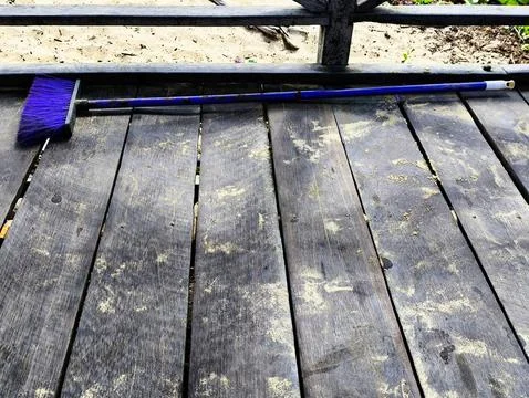 A bright blue plastic broom lying flat on the plank floor of a wooden bridge Stock Photos