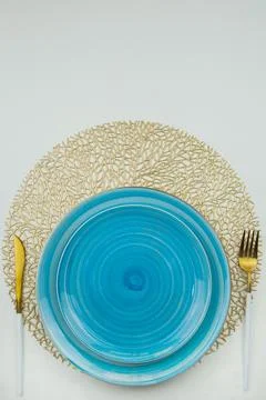 Bright blue serving plates stand on golden air-twisted napkins, on the sides are Stock Photos
