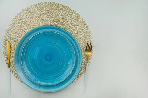 Bright blue serving plates stand on golden air-twisted napkins, on the sides are Stock Photos