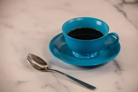 Bright blue simple tea cup and serving saucer with table spoon Stock Photos