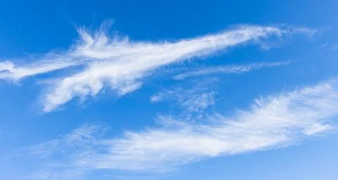 A bright blue sky backdrop with soft, white wispy clouds drifting across th.. Stock Photos