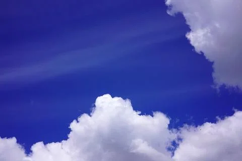 Bright blue sky background with dramatic white cumulus clouds at the bottom Stockfoto's