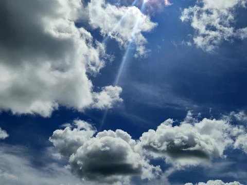 Bright blue sky with dramatic clouds and sun rays Stock Photos