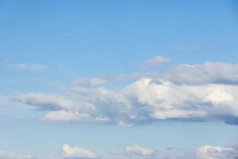 Bright blue sky filled with soft white clouds and a peaceful horizon Stock Photos