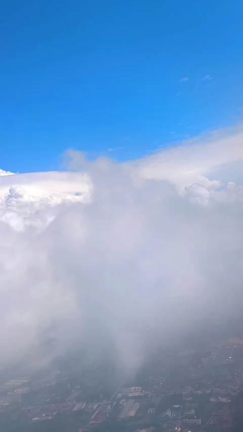 Bright blue sky with fluffy clouds, showing view of islands and cityscape below 스톡 동영상 312729606