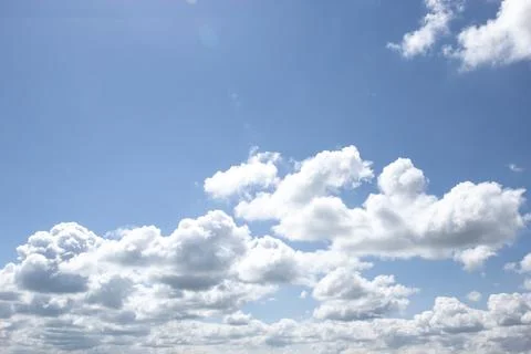 Bright blue sky with fluffy white cumulus clouds and aircraft contrails Stock Photos