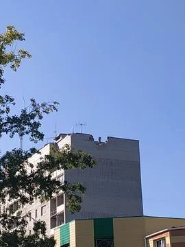 A bright blue sky frames the top of a concrete building with antennas in an.. Stock Photos