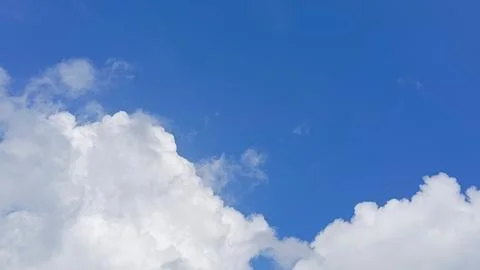 Bright blue sky with large, soft white clouds creating a peaceful and natural Foto stock