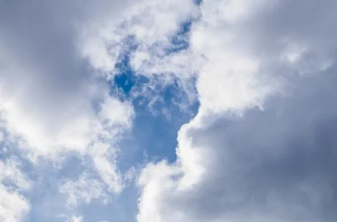 Bright blue sky peeks through the white cumulus clouds on a sunny day. Stock Photos