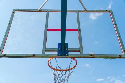 Bright blue sky serves as a backdrop for a weathered basketball hoop, invit.. Stock Photos