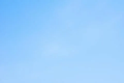 Bright blue sky with soft clouds over a peaceful landscape at midday Stock Photos