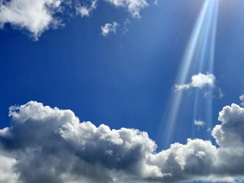 Bright blue sky with sun rays and clouds Stock Photos