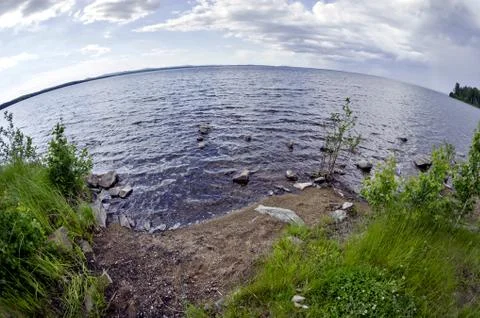 Bright blue sky with white clouds over the shore of the lake Stock Photos