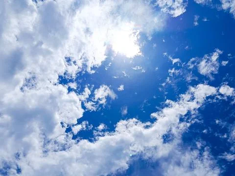 Bright Blue Sky with White Clouds and Shining Sun Stock Photos