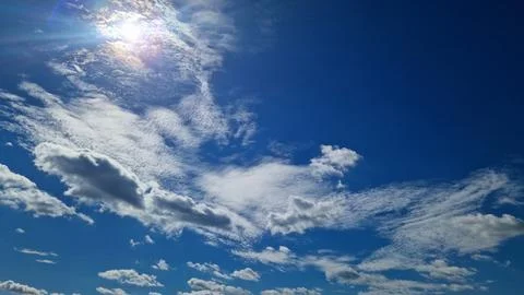 Bright blue sky with white fluffy clouds and sunlight Stock Photos