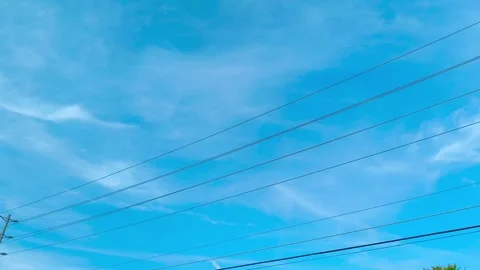 Bright blue sky with wispy clouds and green tree branches creates a peaceful, 動画素材 318310947