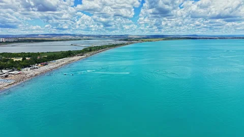Bright blue waters by the shore show coastline and clouds in a sunny sky in a Stock Footage 339519982