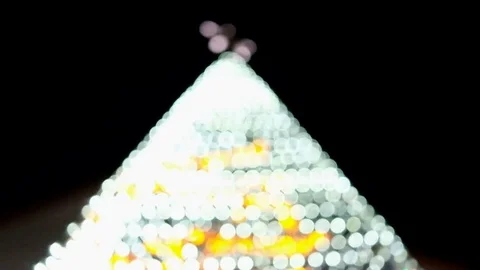 Bright bokeh pyramid shape as christmas tree from low angle view Stock Footage 83654902