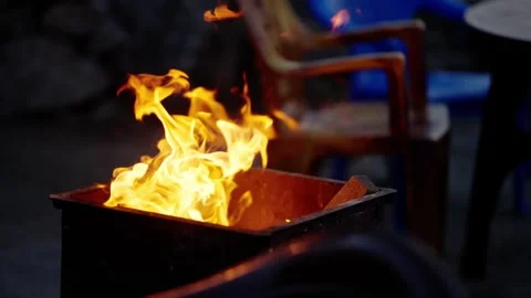 Bright bonfire flames burning in a metal fire pit at a rustic campsite Vídeos de archivo 343142367