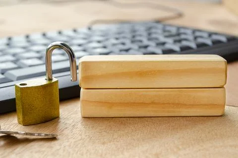 A bright brass padlock positioned on a desk near a computer keyboard with b.. Stock Photos