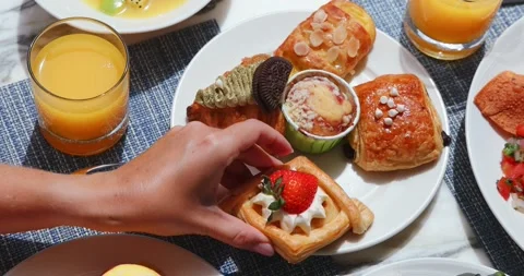 Bright breakfast scene with hand reaching for assorted pastries on Stock Footage 318118495