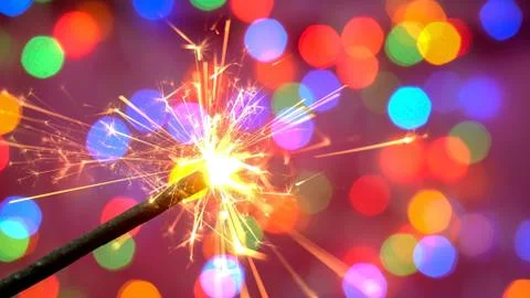 Bright burning sparkler against the backdrop of defocused multicolored garlan Stock Photos