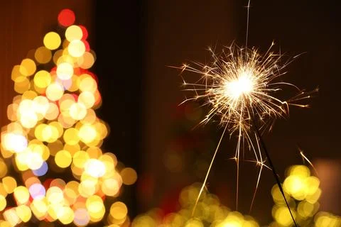 Bright burning sparkler on blurred background, space for text. Bokeh effect Stock Photos