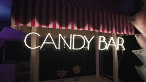 Bright candy bar neon sign mounted on decorative stand at indoor celebration. Stock Footage 332089534