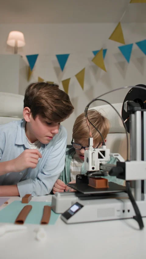 In bright classroom two boys chat and watch a 3D printer work and play with it Stock Footage 335391842