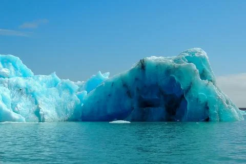 Bright clear blue iceberg floating in the Jokulsarlon lake blue cold water .. Stock Photos