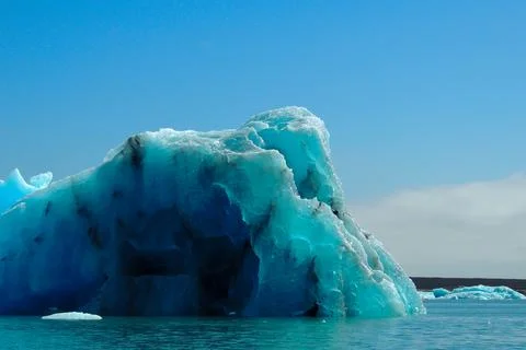 Bright clear blue iceberg floating in the Jokulsarlon lake blue cold water .. Stock Photos