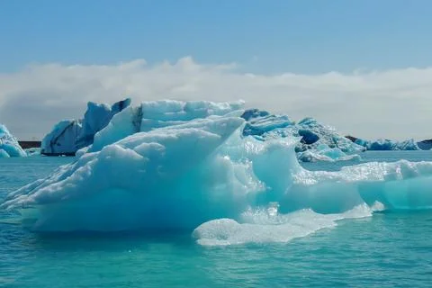 Bright clear blue iceberg floating in the Jokulsarlon lake blue cold water .. Stock Photos