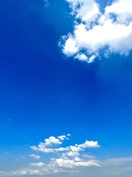 Bright clear blue sky background with soft white fluffy clouds on a sunny day Stock Photos