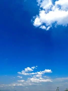 Bright clear blue sky background with soft white fluffy clouds on a sunny day Stock Photos