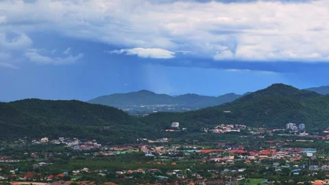 Bright clearing in sky contrasts with rain shadow over tropical hillside city 스톡 동영상 314358023