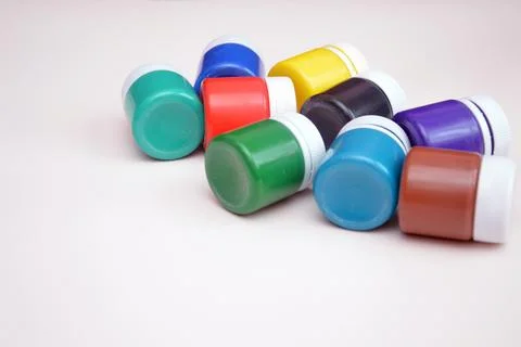 Bright closed jars with multi-colored gouache paints on a light background. D Foto stock