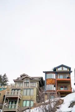 Bright cloud filled sky over homes built on a snow covered hill in winter Stock Photos
