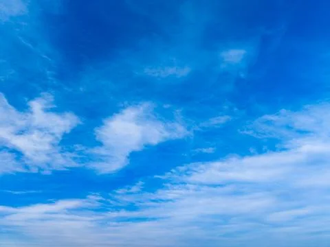 Bright clouds drift in a blue sky with a mix of white and light gray shades.  Stock Photos