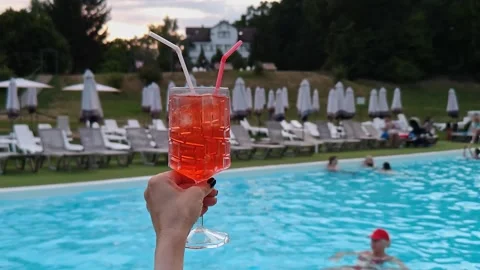 A bright cocktail in hands against the backdrop of a swimming pool Stock Footage 342593191