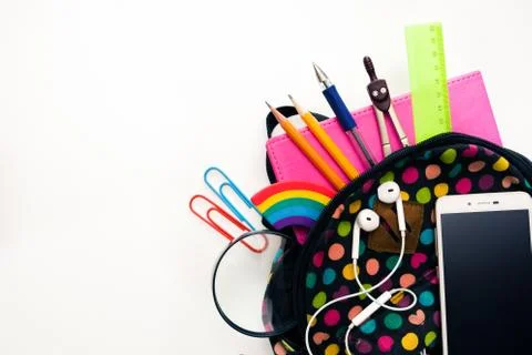 Bright colored backpack, full of school supplies, blank cell phone screen, he Stock Photos