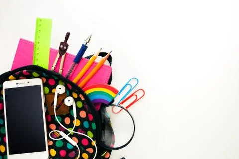 Bright colored backpack, full of school supplies, blank cell phone screen, he Stock Photos
