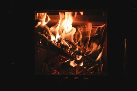 Bright colored dancing flames in fireplace. Close up of burning firewood. Coz Stock Photos