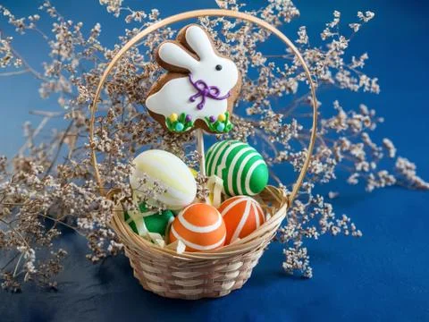 Bright colored Easter eggs and gingerbread in the shape of a rabbit with a wi Stock Photos