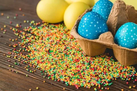 Bright colored Easter eggs in a box on a wooden table Stock Photos