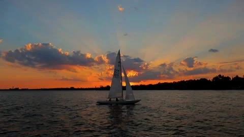Bright colored sunset on the lake. A sailing yacht with a white sail  Video stock 260447234