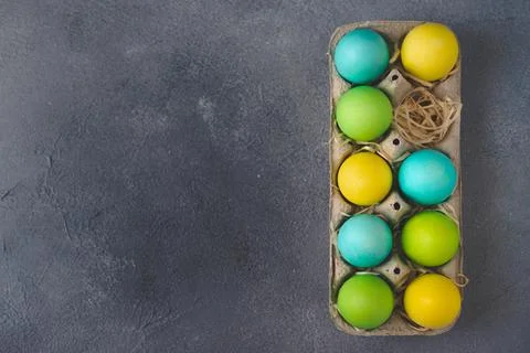 Bright colorful easter eggs in egg carton on grey background. Top view, Copy Stock Photos