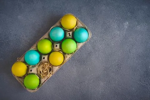 Bright colorful easter eggs in egg carton on grey background. Top view, Copy Stock Photos