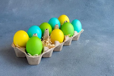 Bright colorful easter eggs in egg carton on grey background Stock Photos