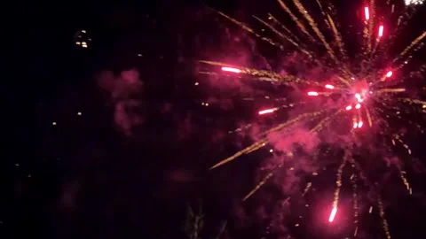 Bright colorful fireworks exploding against a dark night sky creating an Video stock 345832158
